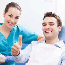 Smiling man in dental chair giving thumbs up