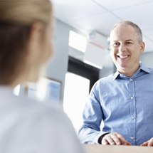 An older man smiling at a dental employee.