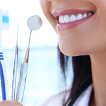 Closeup of woman holding toothbrush and dental hygiene tools