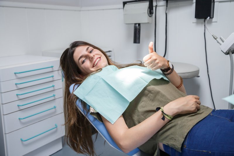 woman giving thumb up in dentist chair