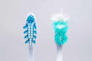 Clean, new toothbrush next to an old, frayed one